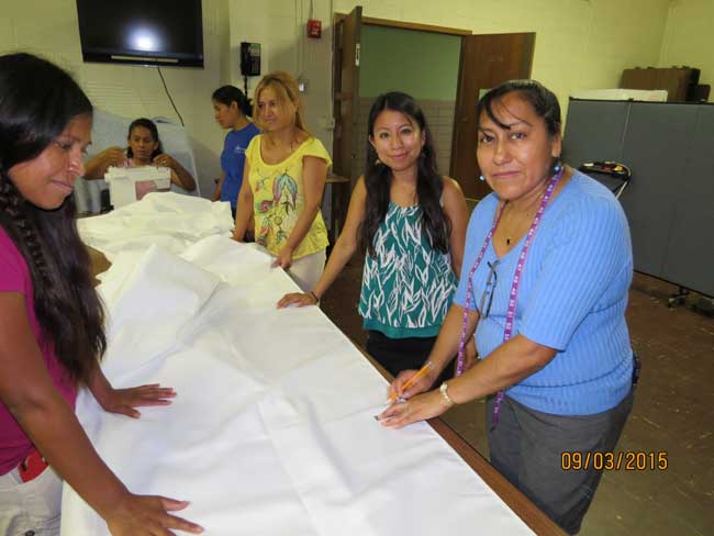 Otro grupo de madres, junto a la directora ejecutiva, Esmeralda Hoscoy, trazando la tela que servirá para preparar los manteles para el Papa