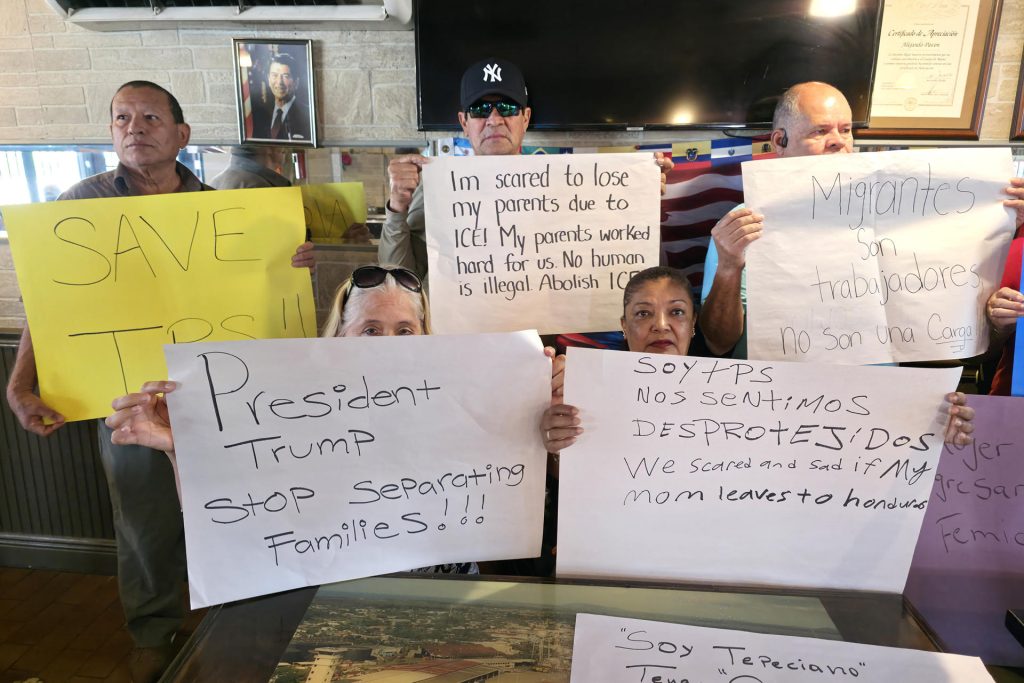 Migrantes beneficiados con el TPS sostienen carteles durante una rueda de prensa este lunes, en la Pequeña Habana en Miami. EFE