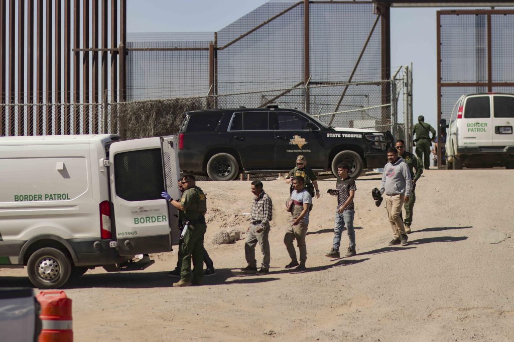 Migrantes detenidos son llevados por miembros de la Patrulla Fronteriza estadounidense a un vehículo, junto al muro fronterizo en El Paso, Texas (EE.UU). Imagen de archivo. EFE